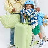 Child with a sky blue helmet green suitcase, surrounded by adults with bags and a teddy bear on a white background