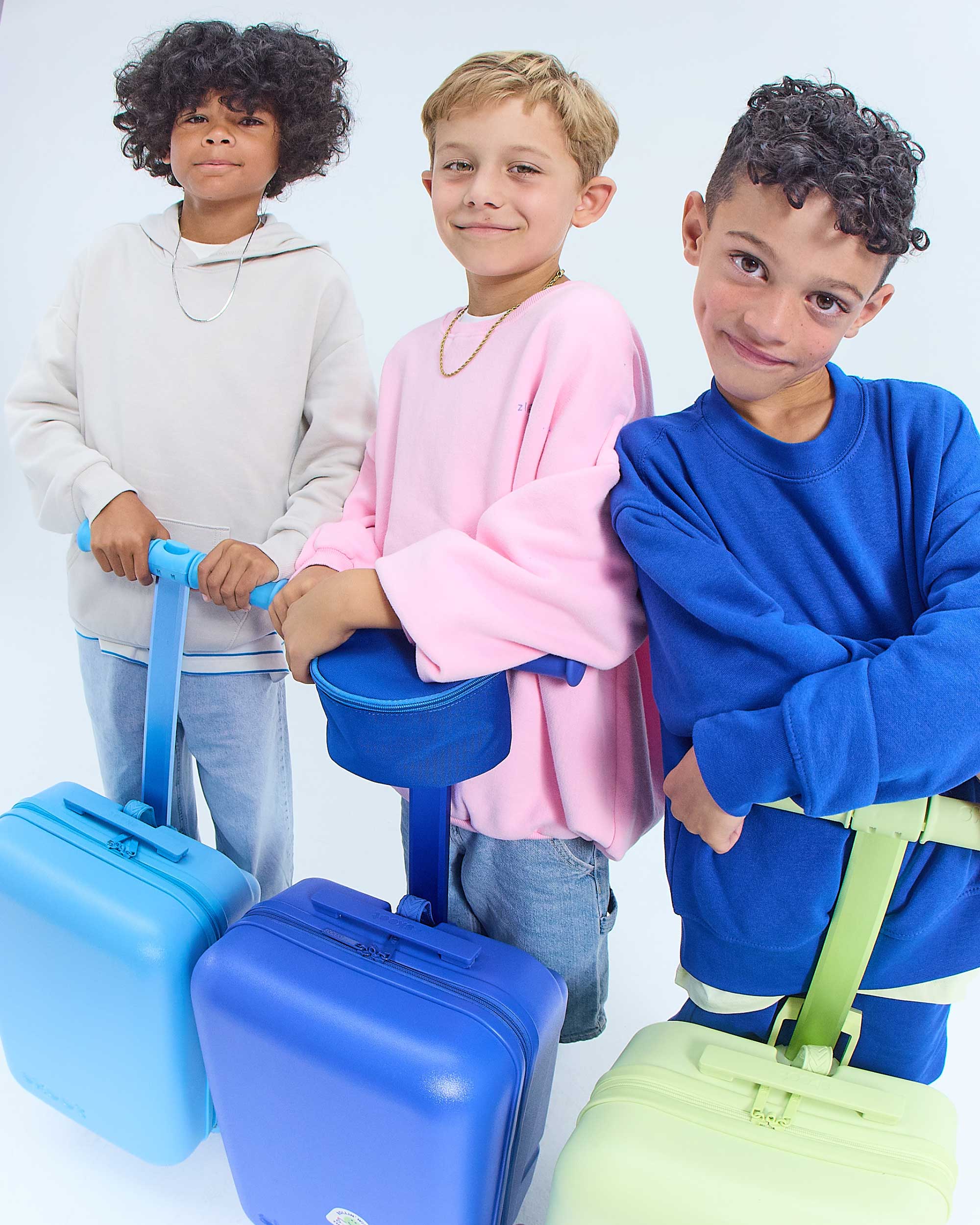 Three children with blue suitcases on a white background jet blue zip pouch blue/green gingham zip pouch pink gingham zip pouch