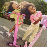 Two children playing with pink skoot skootcases on a sunny day.