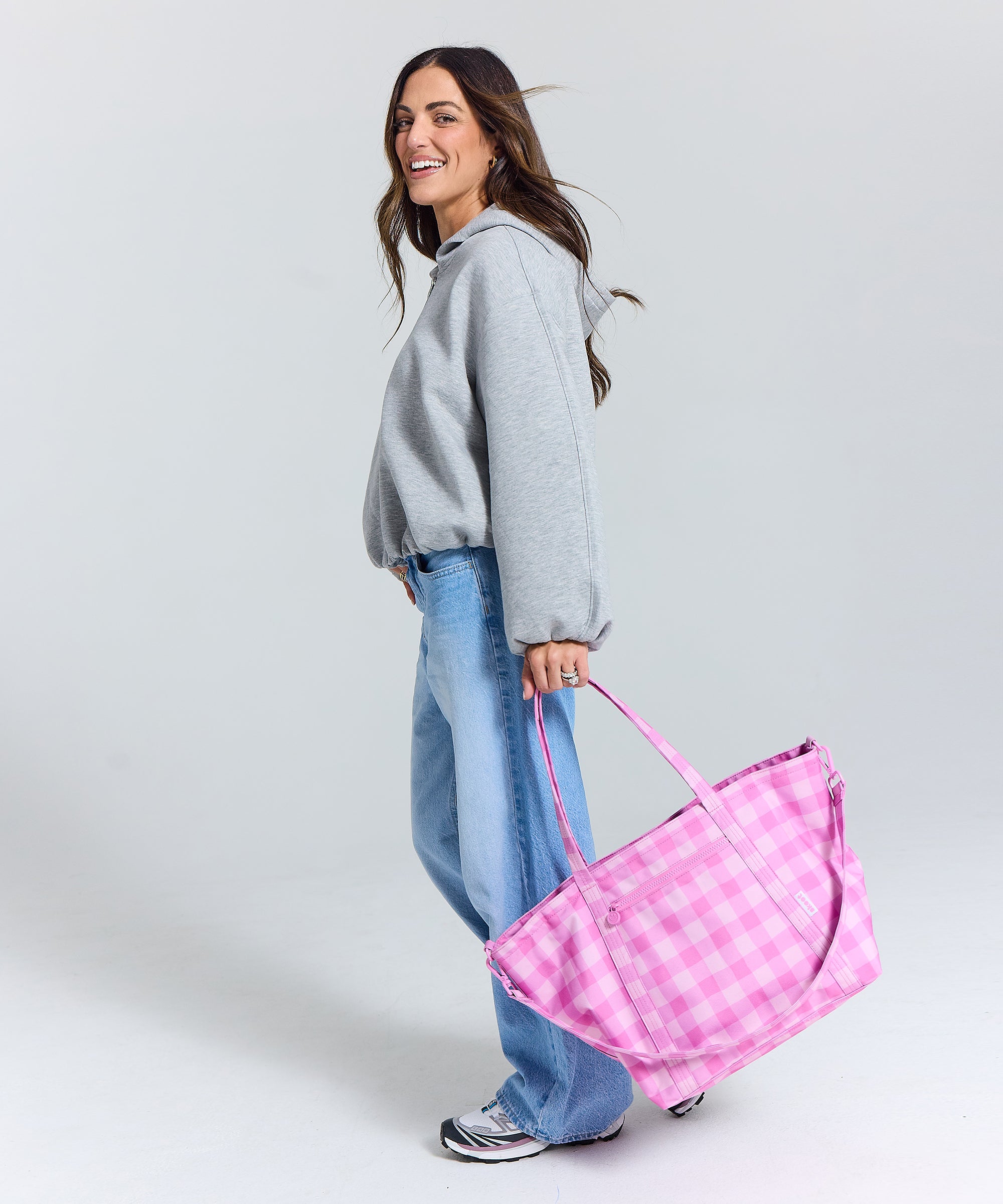 Madi nelson smiling holding the skoot pink gingham tote bag pink gingham