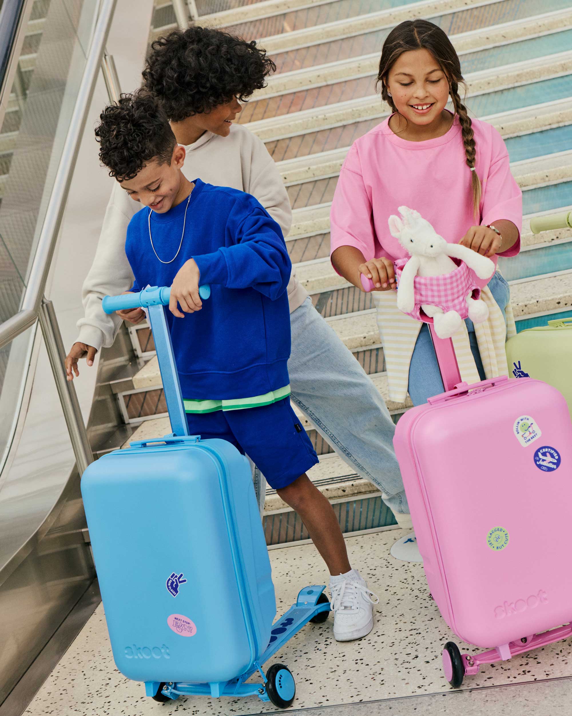 Skoot kids riding skootcases at airport with skoot colors travel stickers